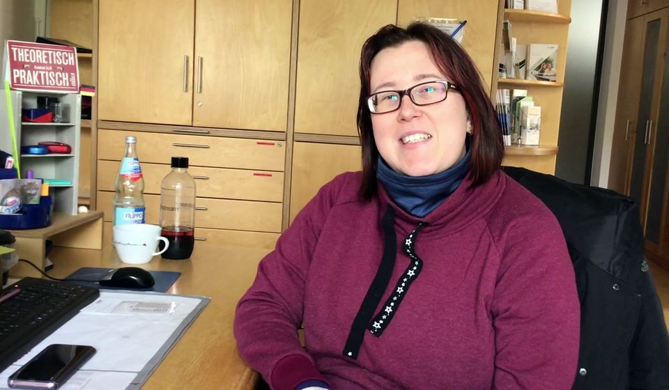 Eine Frau sitzt in einem Büro und blickt in die Kamera