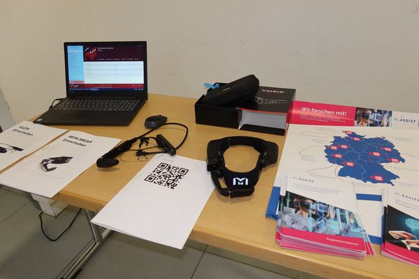 Ein Tisch auf dem ein Laptop, eine VR Brille und Papiere liegen.