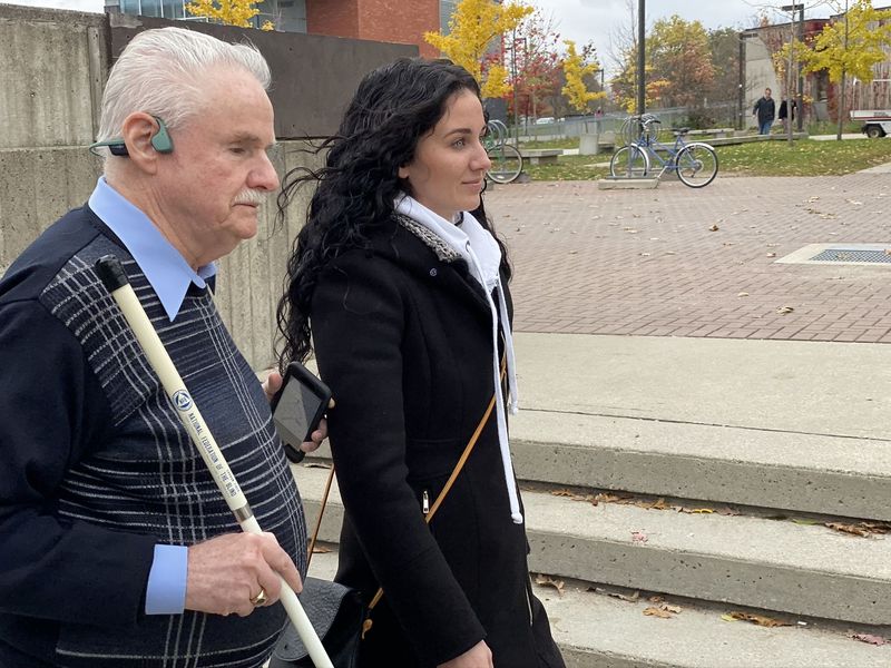 Eine blinder Mann nutzt mit Hilfe einer Begleitung BlindSquare