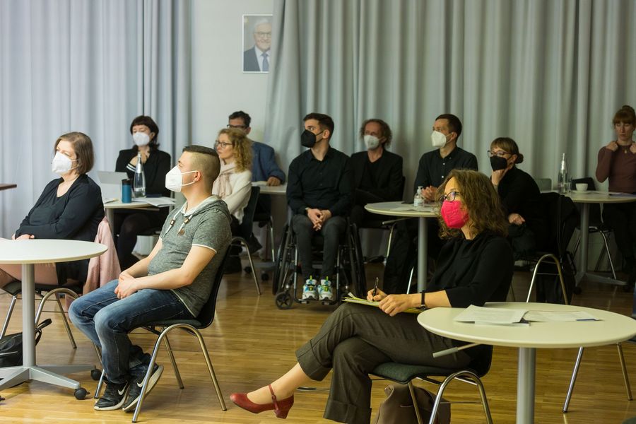 Mehrere der Beteiligten sitzen auf Stühlen und schauen in eine Richtung