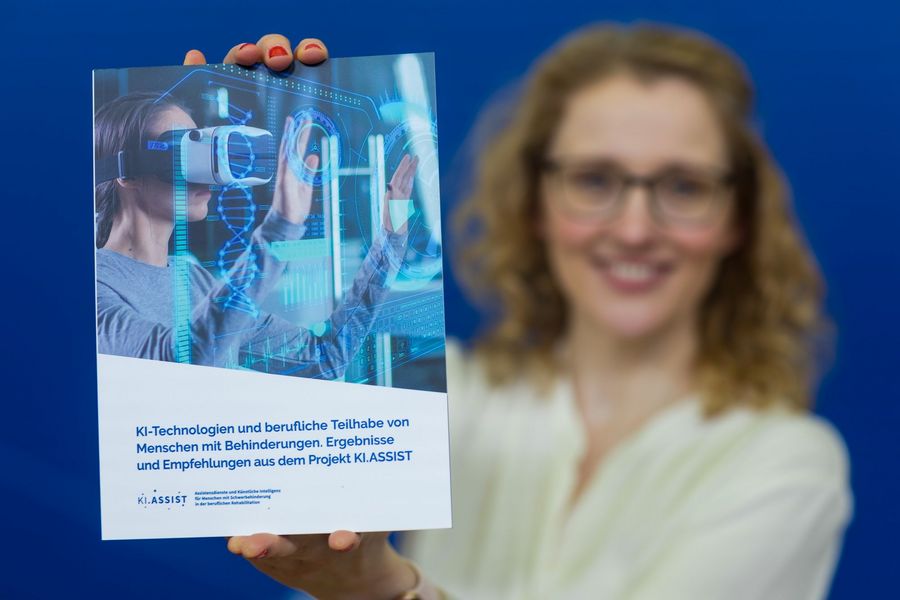 Dr. Susanne Bartel hält die Abschlussbroschüre vom Projekt KI.ASSIST in die Kamera