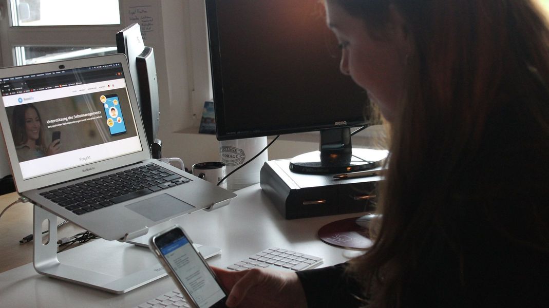 Frau guckt auf ein Smartphone mit AwareMe-App