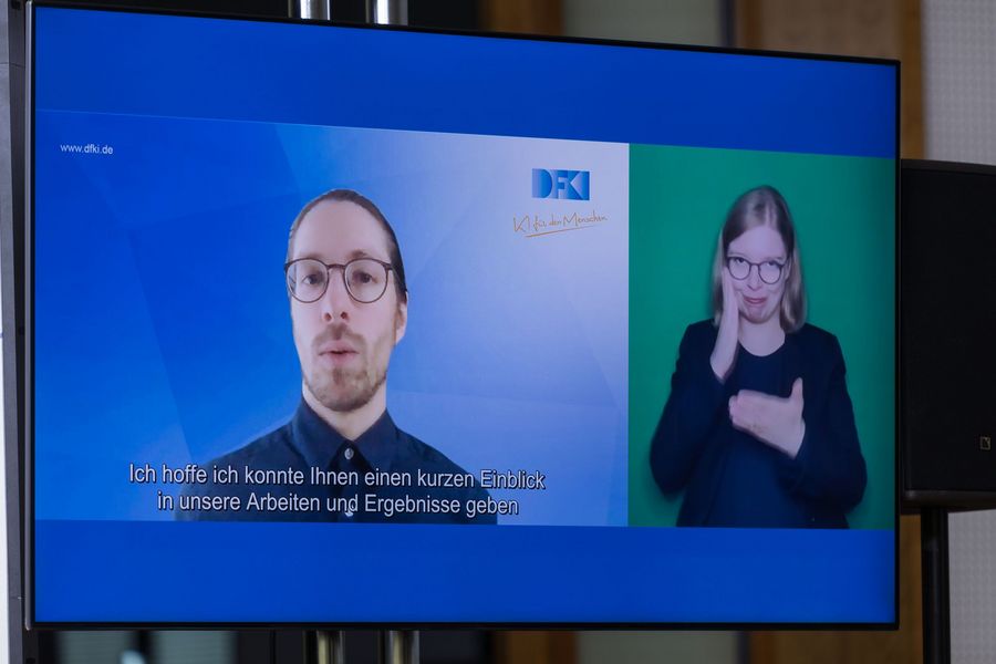 Rolf Feichtenbeiner vom DFKI zugeschaltet mit Übersetzung in Gebärdensprache