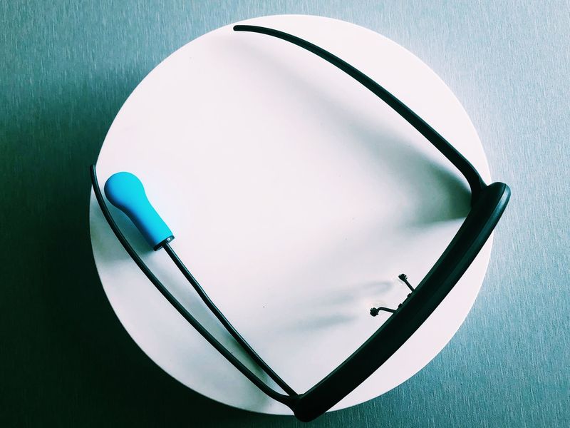 Die assistierende Maus GlassOuse ist von oben abgebildet. Sie sieht aus wie eine schwarze Brille. Der Beiß-Controller ist blau und an der Seite der Brille befestigt.