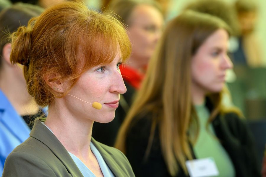 Moderatorin und Teilnehmende hören einem Vortrag zu