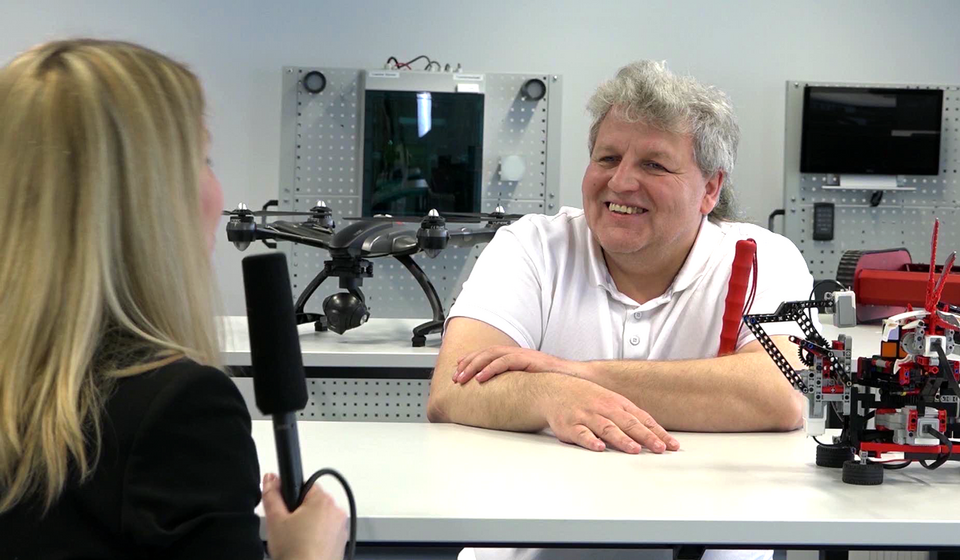 Ein Mann mit Blindenstock wird in einem IT-Labor interviewt