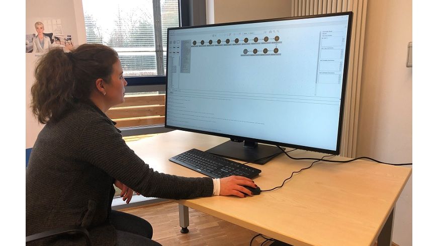 Frau sitzt an einem Tisch vor einem Computer 