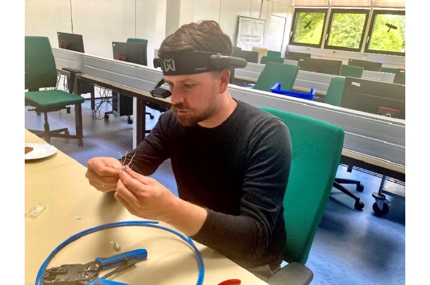 Ein Mann sitzt am Schreibtisch und hat eine AR-Datenbrille auf